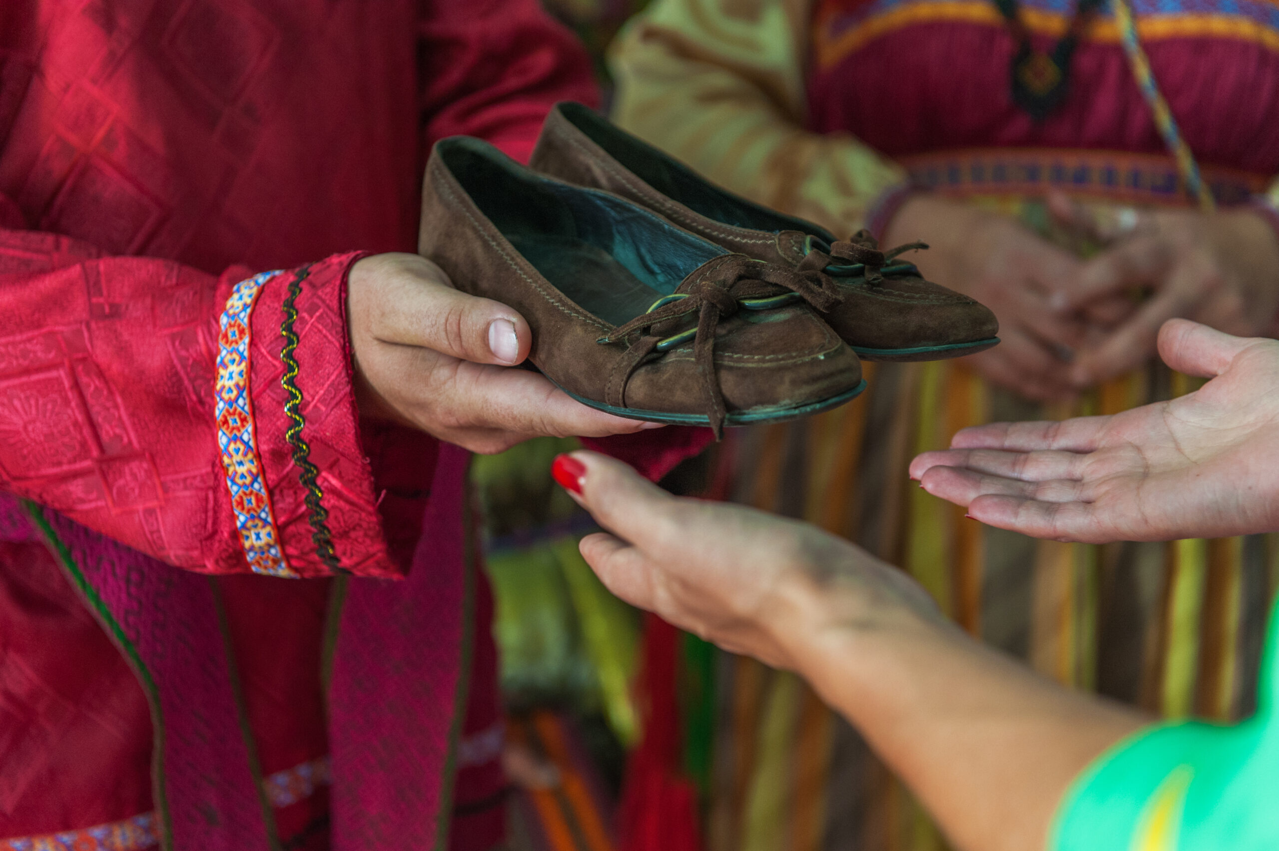 Woman offering shoes to another individual - close up of hands exchanging shoes